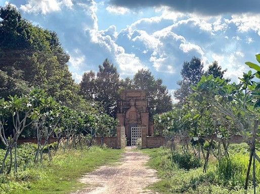 Two rows of frangipani trees lead visitors to the ancient tower